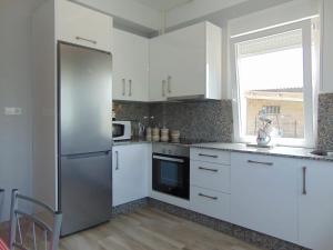 a kitchen with white cabinets and a stainless steel refrigerator at Casa Esperanza 8 huéspedes in Viñas