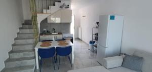 a kitchen with a table with blue chairs and a refrigerator at Heracles Guest house in Nea Peramos