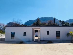 a white building with a door and mountains in the background at Mthiyane Dam View in Hartbeespoort