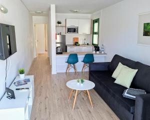 Una sala de estar con un sofá negro y una mesa. en Canaima 223 - Puerto Rico, en Puerto Rico de Gran Canaria
