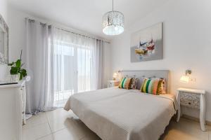 a white bedroom with a bed and a large window at Ocean View Duplex Tenerife ( Golf del Sur) in San Miguel de Abona