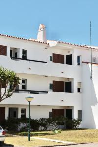 a white building with a palm tree in front of it at Apartamento Malino in Sagres
