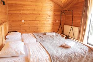 a bedroom with two beds in a wooden cabin at Aronia Kazbegi in Stepantsminda