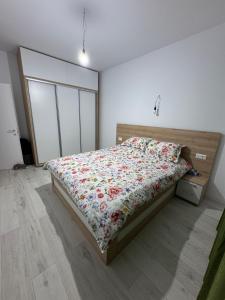 a bedroom with a bed with a floral comforter at Apartament in Ploiești 2 in Ploieşti