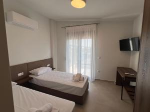 ネア・ムダニアにあるHasi Suites Three Bedroom Duplexのベッド2台とテレビがあるホテルの部屋