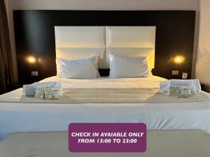 Un dormitorio con una cama grande con sábanas y almohadas blancas. en EH Suites Rome Airport Euro House Hotels, en Fiumicino