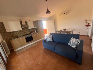 a living room with a blue couch and a kitchen at La Terrazza Sa Cruxitta in Portoscuso +10 photos