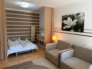 Un dormitorio con una cama, un sofá y una silla. en Art Erika Apartment, en Hajdúszoboszló