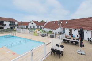 a swimming pool with tables and chairs next to a house at Myfa Beachcottage Zeewind II 270 in Bredene