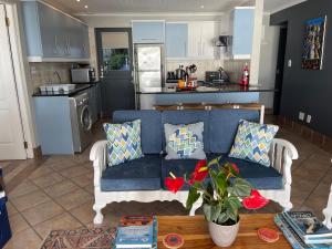 a living room with a blue couch and a kitchen at WhaleTale in De Kelders
