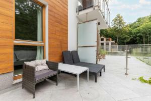 a patio with two chairs and a table at Cosy Apartment Parking & Balcony Close to the Kępa Redłowska by Noclegi Renters in Gdynia