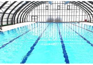 a large indoor swimming pool with blue water at Le Chastellan Twin roomChambre Twin in Péone
