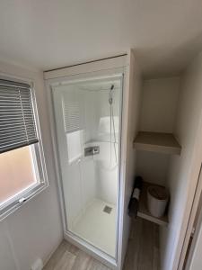 una doccia con una porta in vetro in un bagno di Mobil home familial avec terrasse et bord de mer ad Argelès-sur-Mer Altre 22 foto