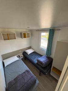 una camera con due letti, un divano e una finestra di Mobil home familial avec terrasse et bord de mer ad Argelès-sur-Mer