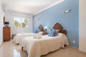 two beds in a room with blue walls at Villa Gloria in Cala Pi +32 photos