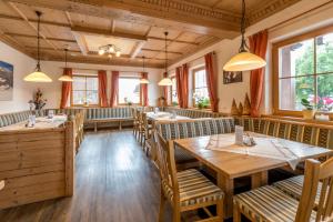 a restaurant with wooden tables and chairs and windows at Peterbauerhof in Ramsau am Dachstein