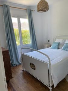 a bedroom with a bed with blue curtains and a window at Maison entre Landes et Pays basque, Plage à 3km in Ondres
