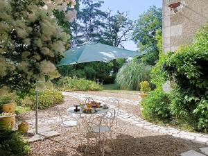 a table with chairs and an umbrella in a garden at Chateau de Coubloust in Vicq-sur-Nahon