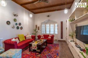 a living room with red couches and a tv at StayVista at Ellis Ville with Bonfire, Lawn in Kasauli