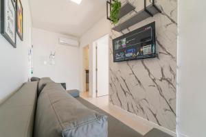 Una sala de estar con un sofá y un televisor en una pared. en HY Apart, en Bombinhas