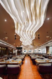 una sala da pranzo con tavoli e sedie sotto un grande lampadario a braccio di SCYLLA Luxury Resort & Spa a Kaup