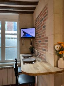 une table de salle à manger avec une télévision sur un mur de briques dans l'établissement Appartement Des Lingots, à Honfleur