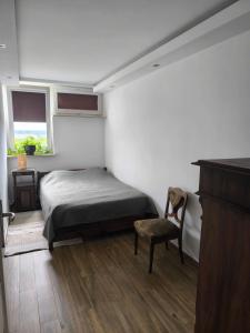 a bedroom with a bed and a chair and a window at Downtown Apartment in Warsaw