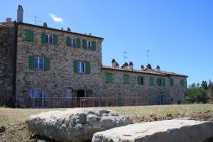 a large stone building with green windows and a rock at La chesa de prìt in Verucchio