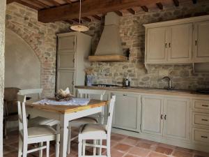 a kitchen with a wooden table and white cabinets at La chesa de prìt in Verucchio