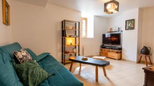 a living room with a green couch and a tv at La proue du serre 4/5 personnes in Sainte-Énimie