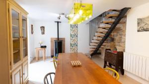 a dining room with a wooden table and a spiral staircase at La proue du serre 4/5 personnes in Sainte-Énimie