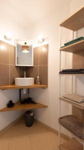a bathroom with a sink and a mirror and shelves at Gîte La Proue du Serre 4/5 personnes in Sainte-Énimie