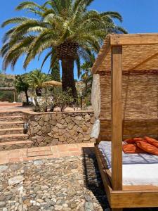 皮萨拉Santa Teresa Bed & Breakfast Andalusien的棕榈树前的一张木床