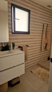 ein Badezimmer mit Waschbecken und Fenster in der Unterkunft Akunamatata in Oliva + 12 Fotos