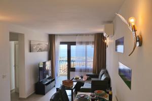ein Wohnzimmer mit einer Couch, einem Tisch und einem Fernseher in der Unterkunft Paradise Ocean View in Los Cristianos