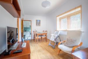 un salon avec une télévision et une table avec des chaises dans l'établissement Ostoja przy potoku- z tarasem oraz parkingiem- BestRooms, à Międzybrodzie Żywieckie