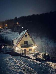 une maison dans la neige la nuit avec des lumières dans l'établissement Ostoja przy potoku- z tarasem oraz parkingiem- BestRooms, à Międzybrodzie Żywieckie