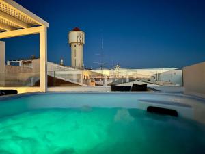 a swimming pool with a lighthouse in the background at Casa da Praça - Vila do Bispo, Algarve in Vila do Bispo