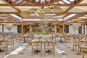 a restaurant with wooden ceilings and tables and chairs at JAZ Almaza BLU, Almaza Bay in Marsa Matruh