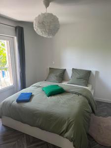 ein Schlafzimmer mit einem Bett mit grüner Bettwäsche und einem Fenster in der Unterkunft Appartement en cœur de village au pied du château avec 2 balcons in Alba-la-Romaine