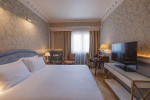 a hotel room with a bed and a flat screen tv at Mediterranean Palace in Thessaloniki