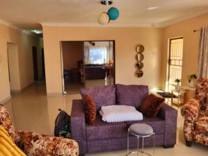 a living room with a purple couch and chairs at BRT Apartments in Livingstone
