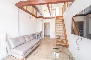 un salon avec un canapé et un escalier en bois dans l'établissement Charmante Maisonette im Herzen des Magniviertels - Stilvoll, Zentral & Gemütlich, à Brunswick