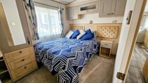 a bedroom with a bed with a blue and white comforter at Lakeside Lodge - Jet Ski Lake in Tattershall