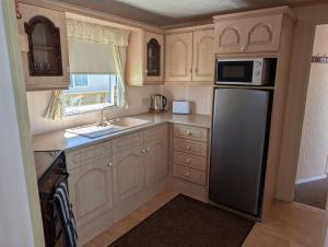 a small kitchen with a refrigerator and a sink at 21 Chestnut Grove in Kirkcolm