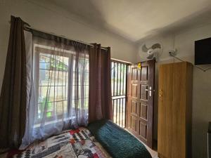 a bedroom with a bed and a window and a door at Proteahill Guesthouse in Drummond