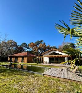 a house with a wooden walkway next to a pond at Villa des Résiniers, proche plage & forêt, wifi in Moliets-et-Maa