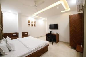 a bedroom with a bed and a desk and a television at Hotel Super Stay in Ujjain