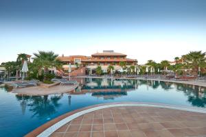 a swimming pool in a resort with palm trees and a building at Monte Santo Resort in Carvoeiro