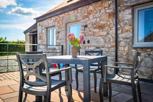 einen Tisch und Stühle auf einer Terrasse mit einem Steingebäude in der Unterkunft Residence Cottage in Beaumaris